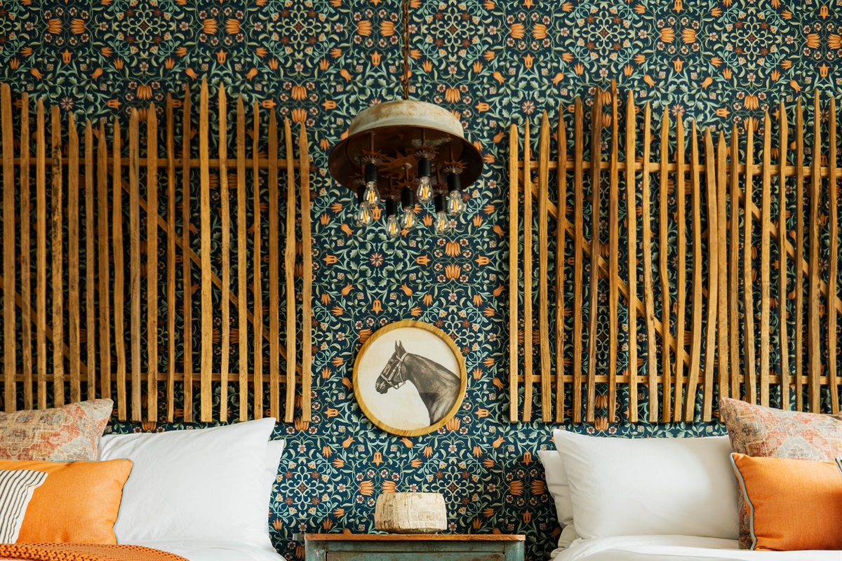 Two queen beds under a custom chandelier at the Corral Suite — designer modern Western lighting upstairs at Gaines Ranch on the Square.