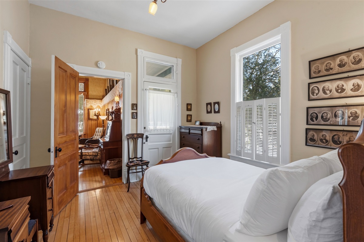 Bedroom view opening into hallway w/ warm wood floors
