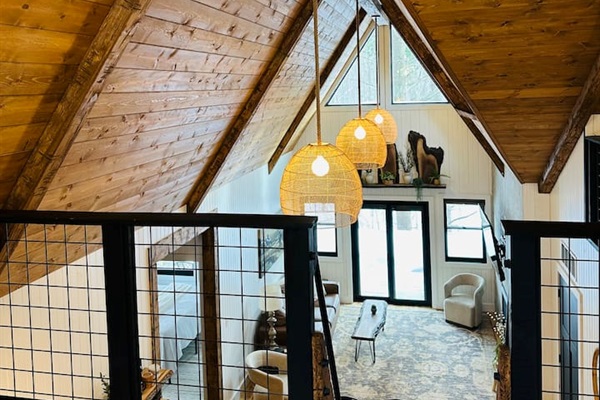 This dreamy second-story loft is accessible only by a ship’s ladder, adding an adventurous yet intimate feel. It features a king bed beneath a dramatic A-frame ceiling. Large triangular windows offer stunning views, making it the perfect hideaway.