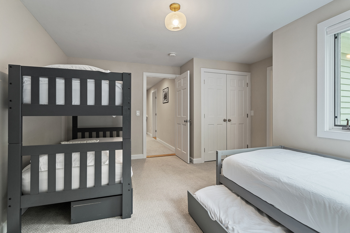 Another view of the bunk room showing the bunk bed and the twin with trundle, with closet storage
