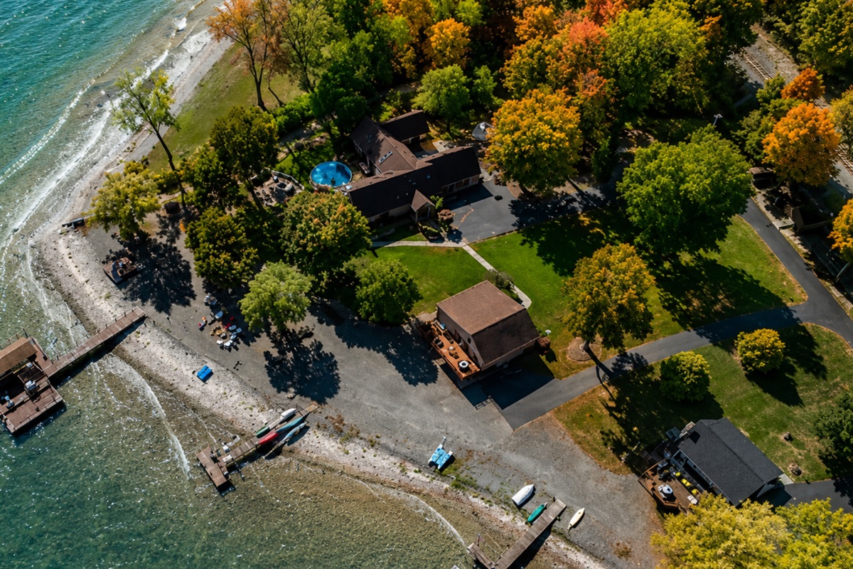 Aerial view of your quiet waterfront retreat surrounded by vibrant fall foliage. Peace, privacy, and lake access all in one.