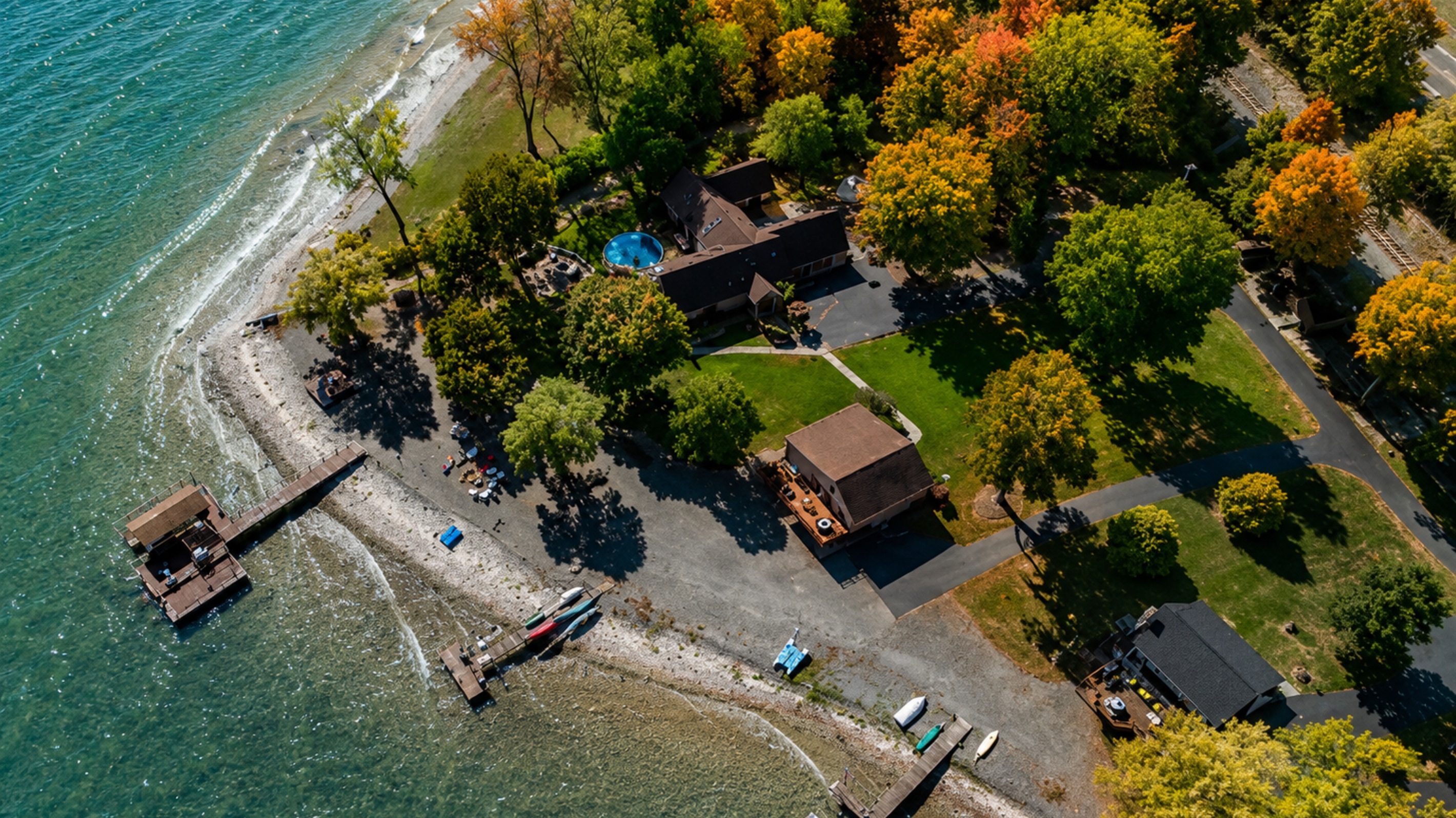 Aerial view of your quiet waterfront retreat surrounded by vibrant fall foliage. Peace, privacy, and lake access all in one.