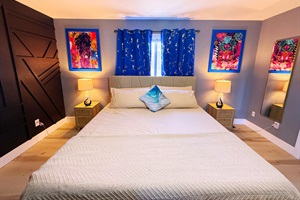 A cozy bedroom filled with artistic charm. The curtains and warm lighting create a relaxing ambiance. A perfect blend of comfort and creativity for a restful stay.