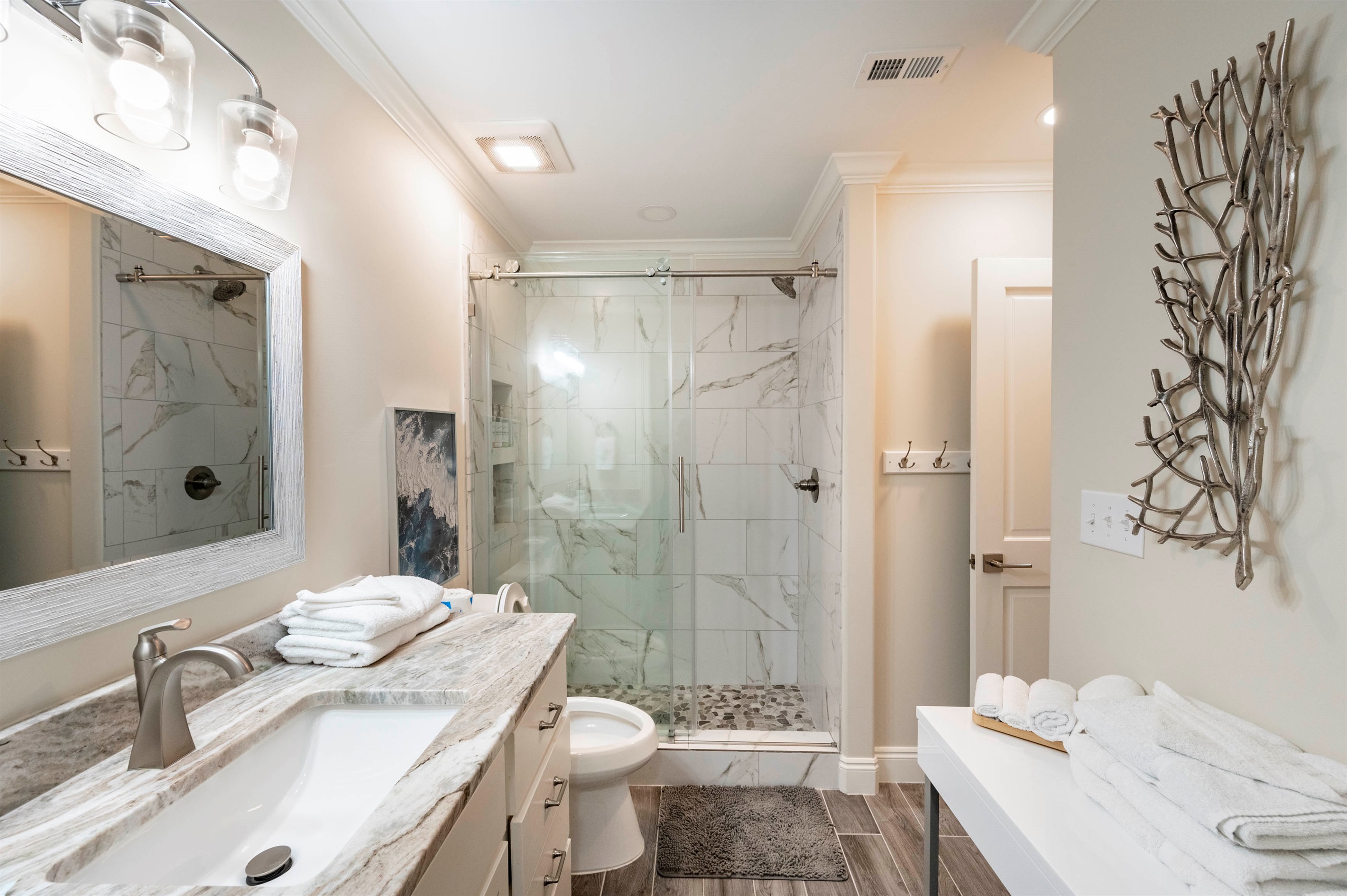 A coastal full bath with a sleek vanity, glass shower, and fresh towels offers a spa-like retreat.
