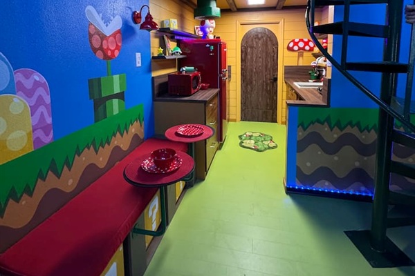 Magical Mario dining area at Mario's Mini Mansion, Clermont, FL! Red bench seating, spiral staircase, and glowing "Mario's Mini Mansion" sign make every meal feel like an adventure.