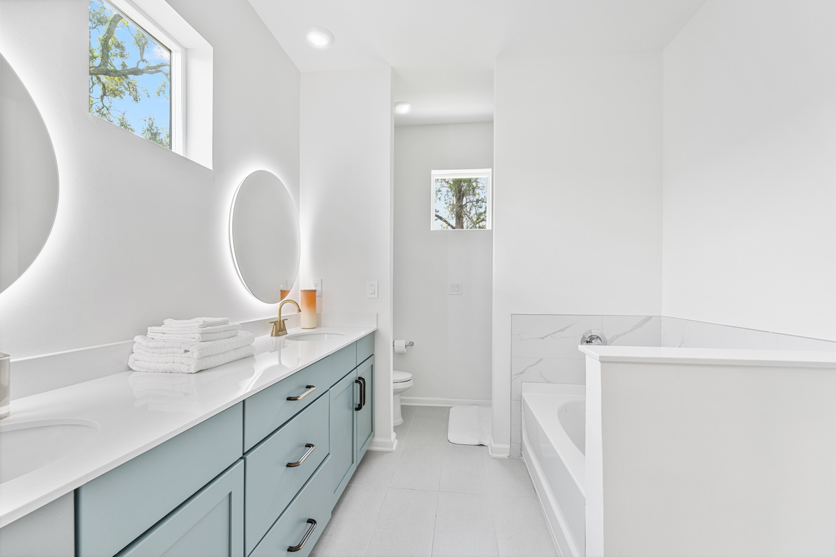 Two sinks mean nobody waits their turn, and that deep tub is calling after a day on your feet downtown. Light spills through the treetop window, the kind of small restorative luxury that makes a trip feel like rest.