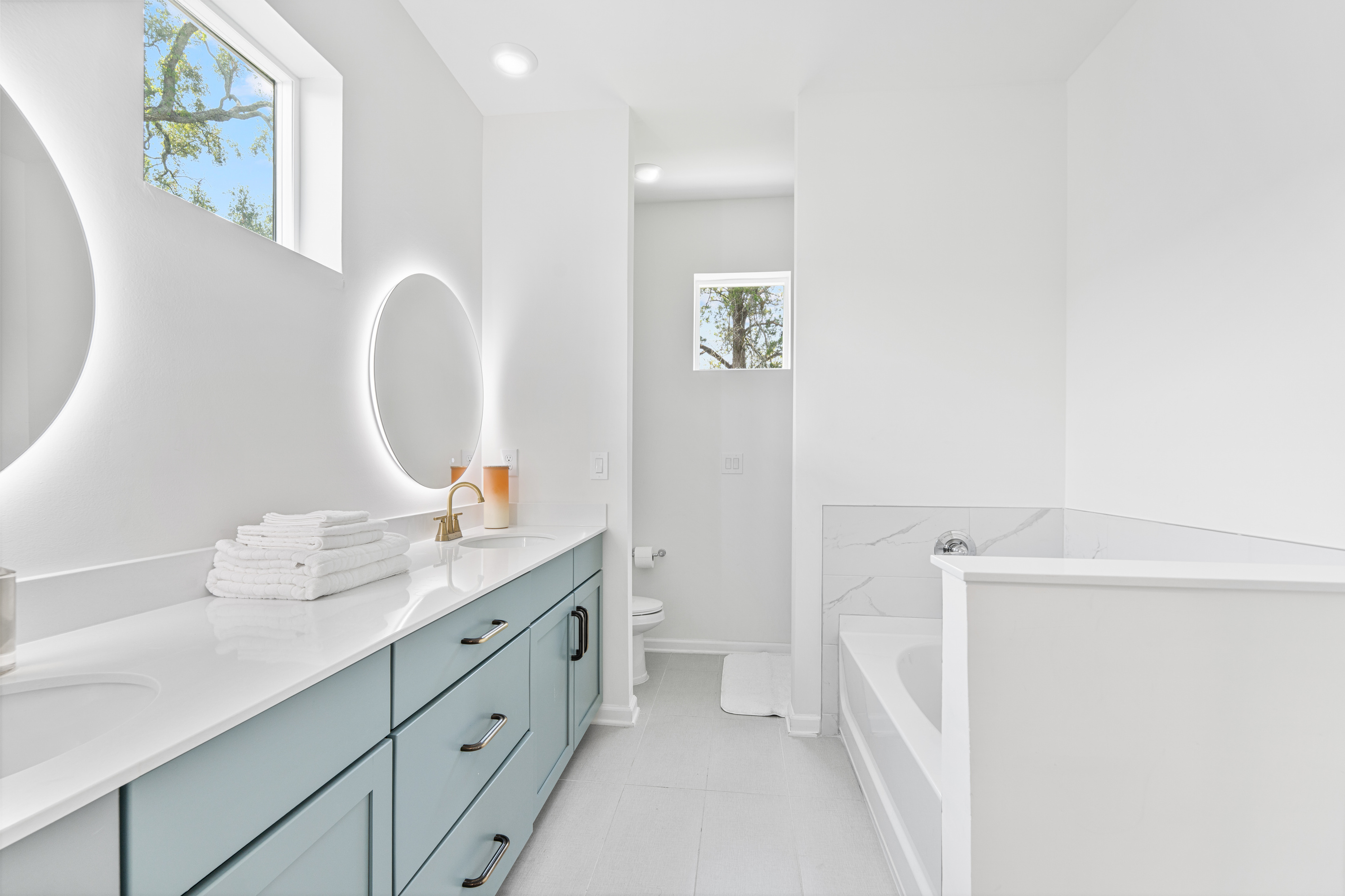 Two sinks mean nobody waits their turn, and that deep tub is calling after a day on your feet downtown. Light spills through the treetop window, the kind of small restorative luxury that makes a trip feel like rest.
