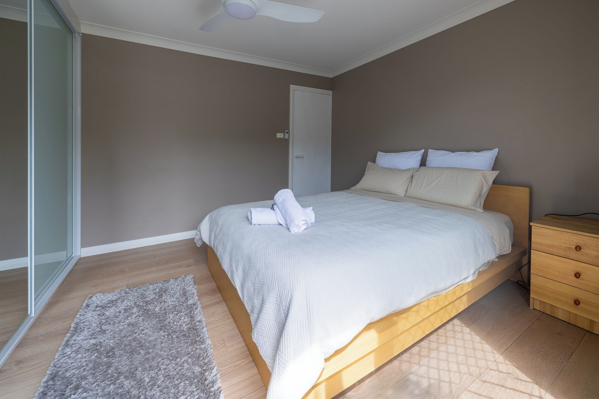 This queen bedroom at Luna’s Sanctuary features a ceiling fan, mirrored wardrobe, timber floors and bedside storage for a practical stay.