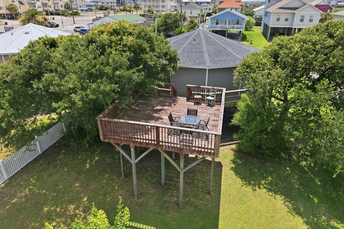 Aerial view showcasing the expansive private upper deck surrounded by mature trees for added privacy