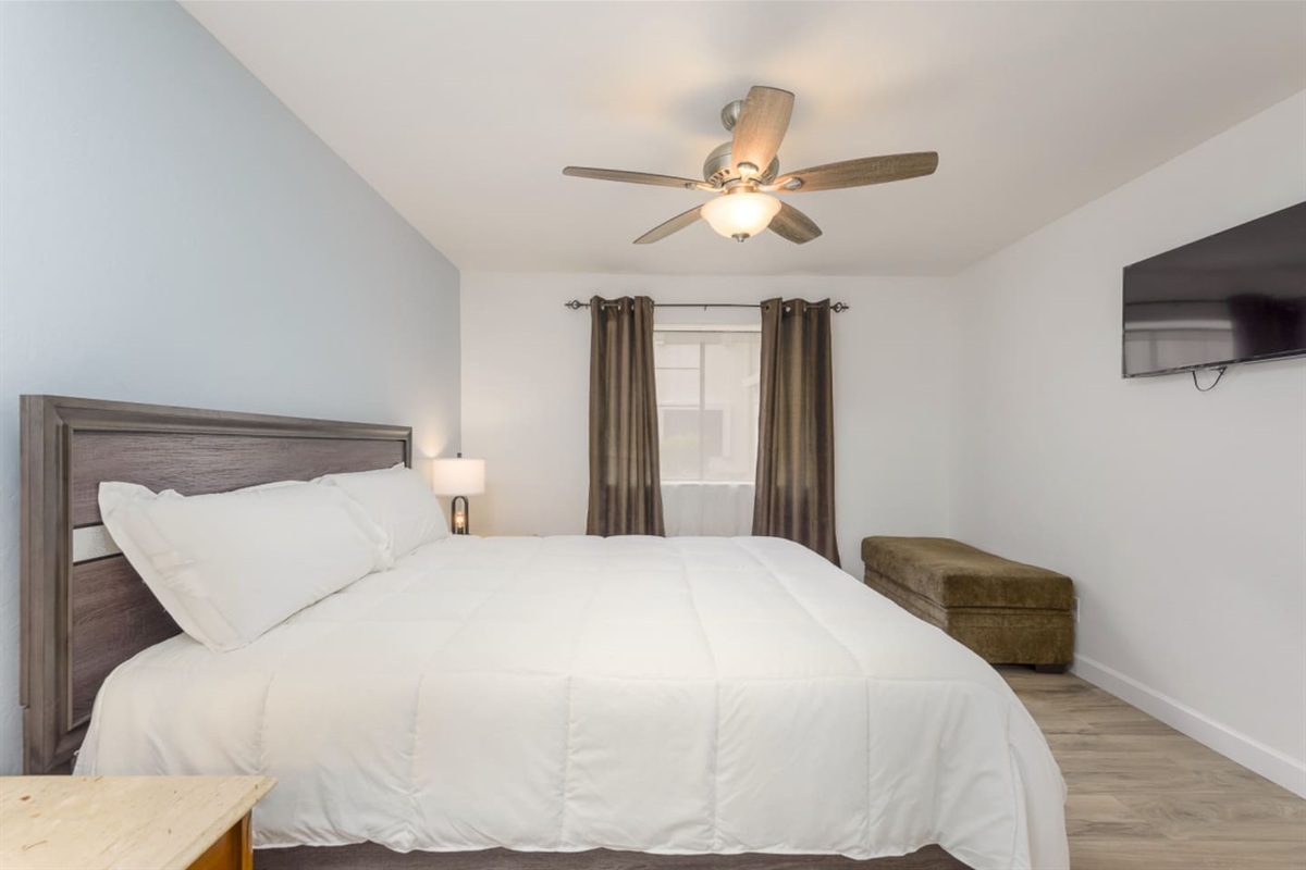 King bedroom with soft bedding, bedside lamps, and a simple place to relax at the end of the day.

