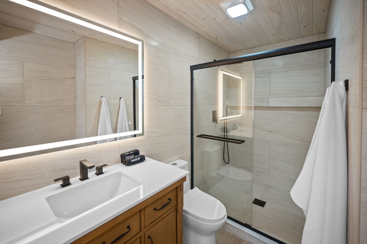 Modern full bathroom with a walk-in shower and lighted mirror.