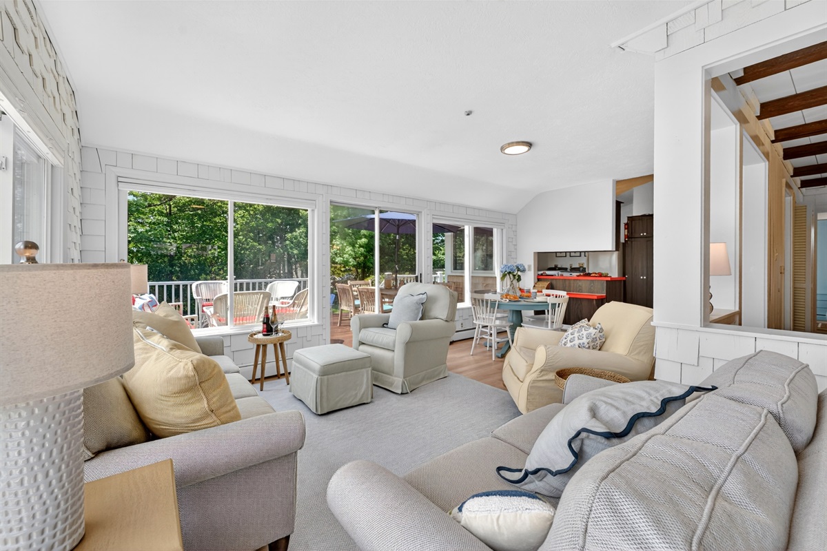Living room filled with natural light from wide windows, creating a bright and airy atmosphere with a cozy and inviting seating area.