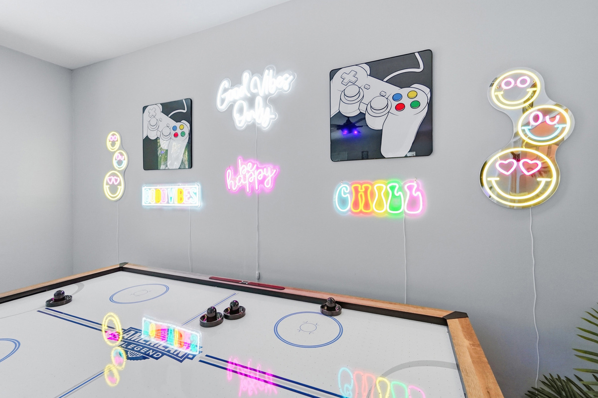 Bright neon d&eacute;cor adds a playful glow above the full-size air hockey table.
