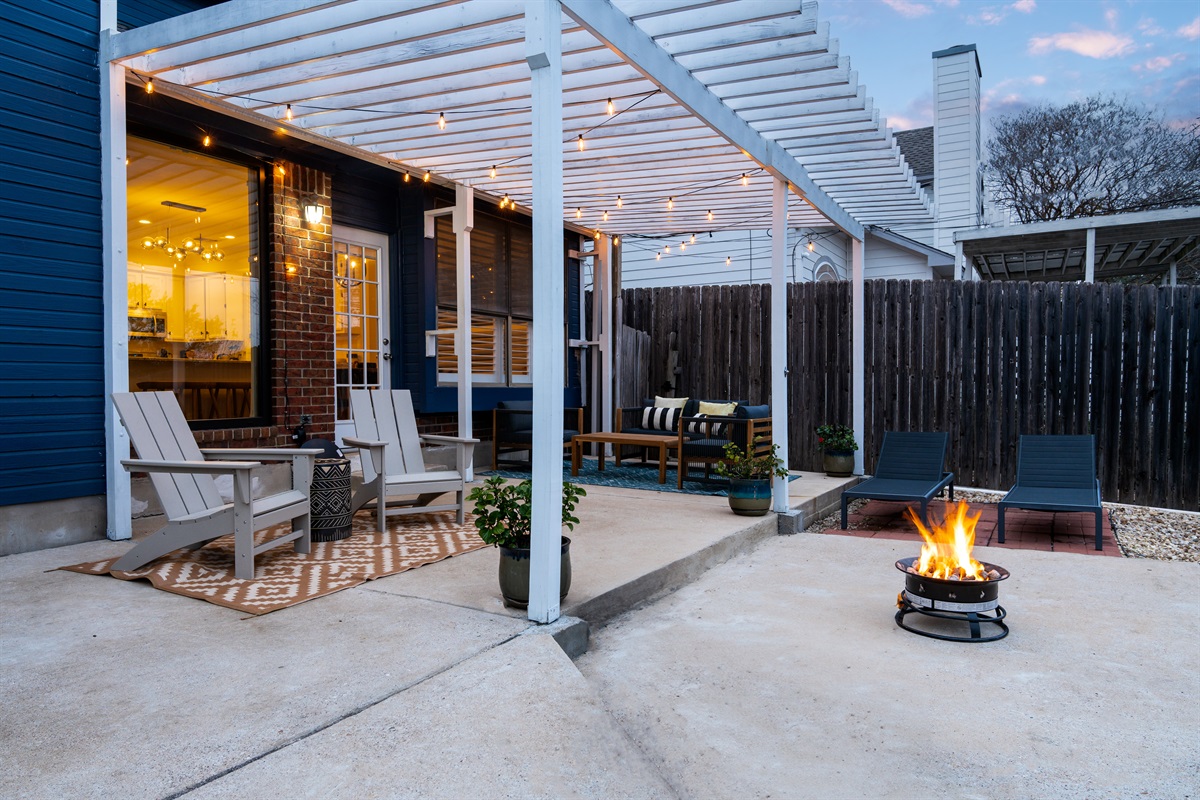 Cozy backyard retreat with a shaded lounge area and a warm, inviting fire pit.