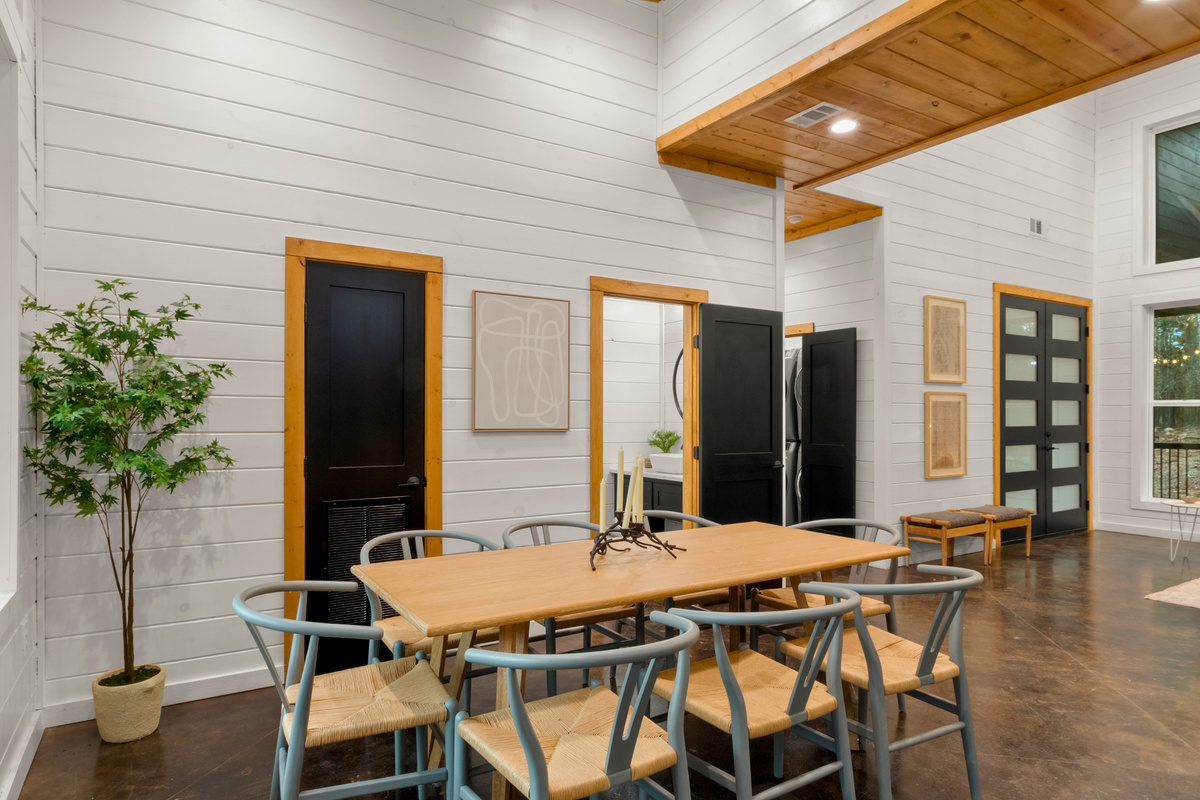 The dining room showcases a sturdy wooden table accompanied by chairs with a touch of color that adds vibrancy to the room