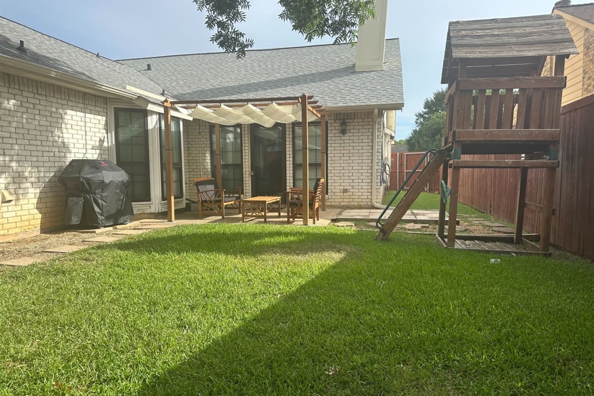 Private backyard with grill, seating, and playset — ideal for family fun.