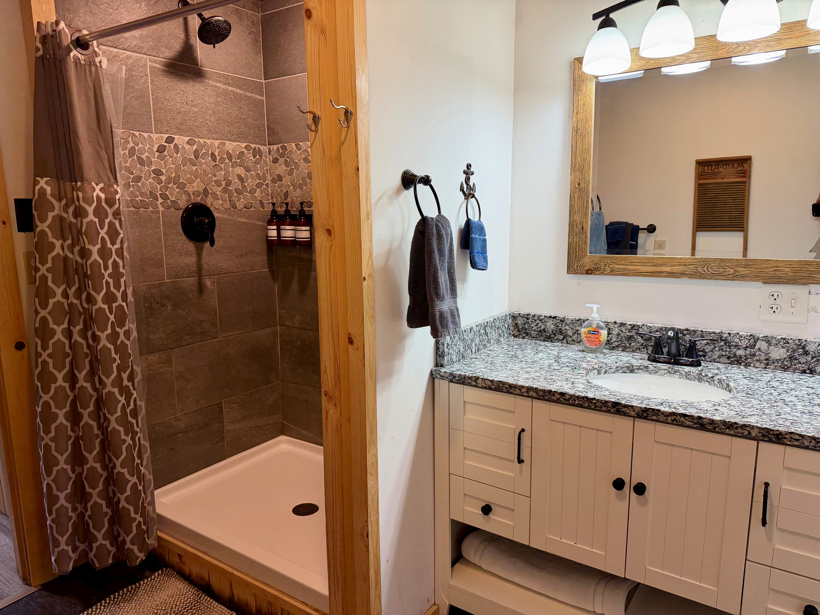 A fresh, modern shower featuring sleek stone tile and a clean, spa like feel. Stocked with wall mounted body wash, shampoo, and conditioner, it’s ready for guests to refresh and unwind in comfort.