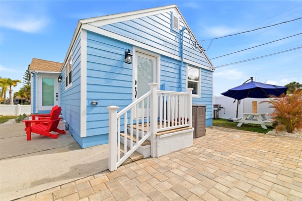 Side patio with beach gear and sports equipment for R.O.C. Park. Inviting outdoor seating area with umbrella and propane grill.