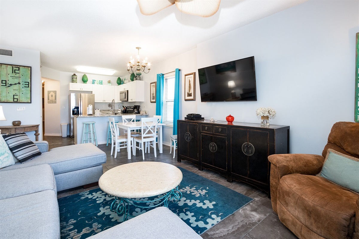 Living room with wall mounted smart TV, ceiling fan, sleeper sofa and balcony access with breathtaking view