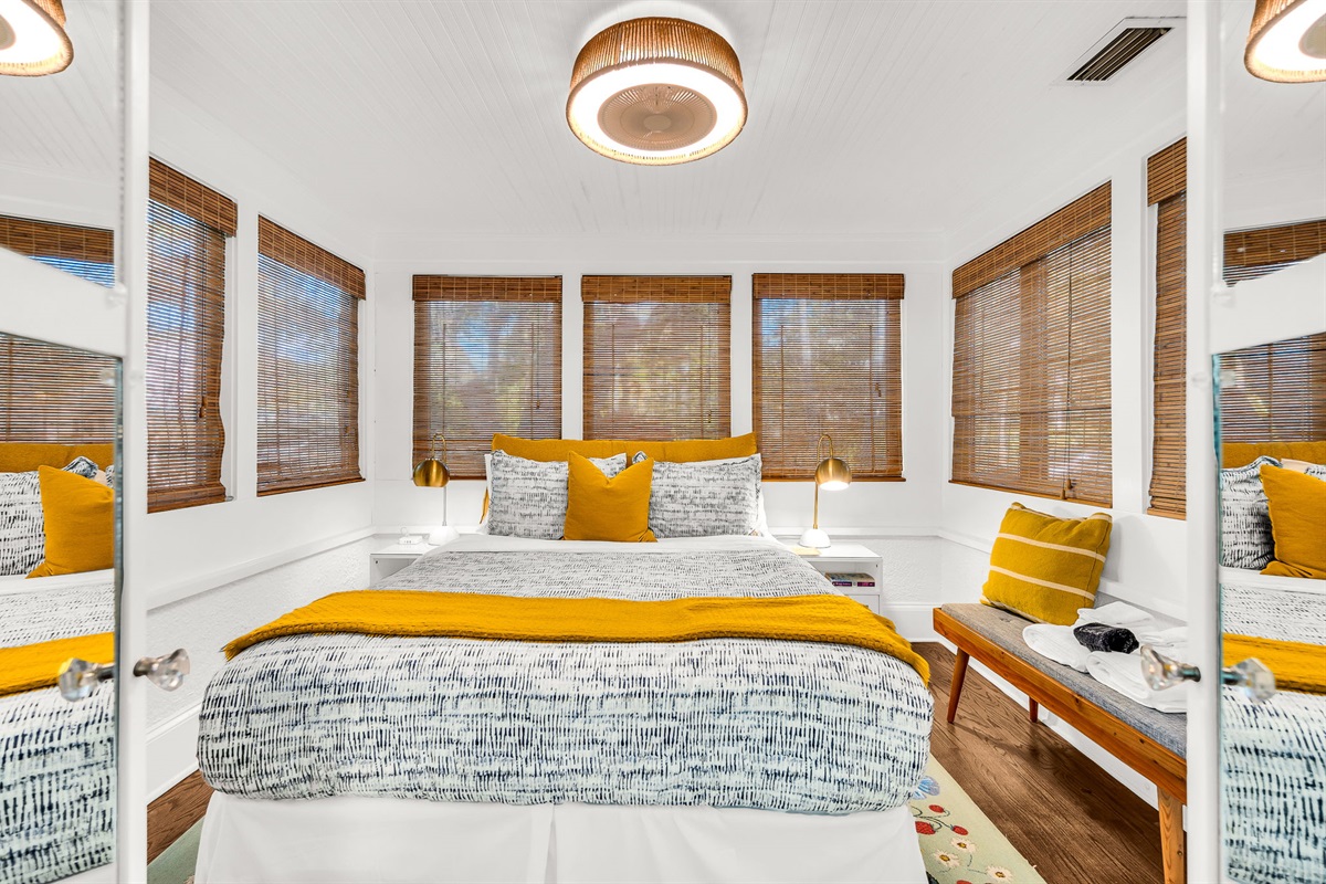 Charming first-floor queen bedroom just off the main living area, featuring a queen bed, a smart TV,  bamboo shades, and French doors that fill the room with natural light.