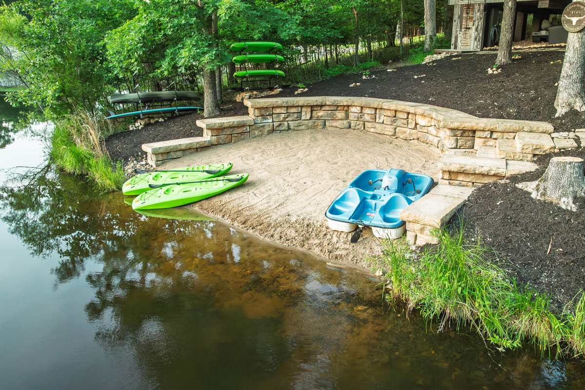 Sandy beach with kayaks and paddle boat included for guests.