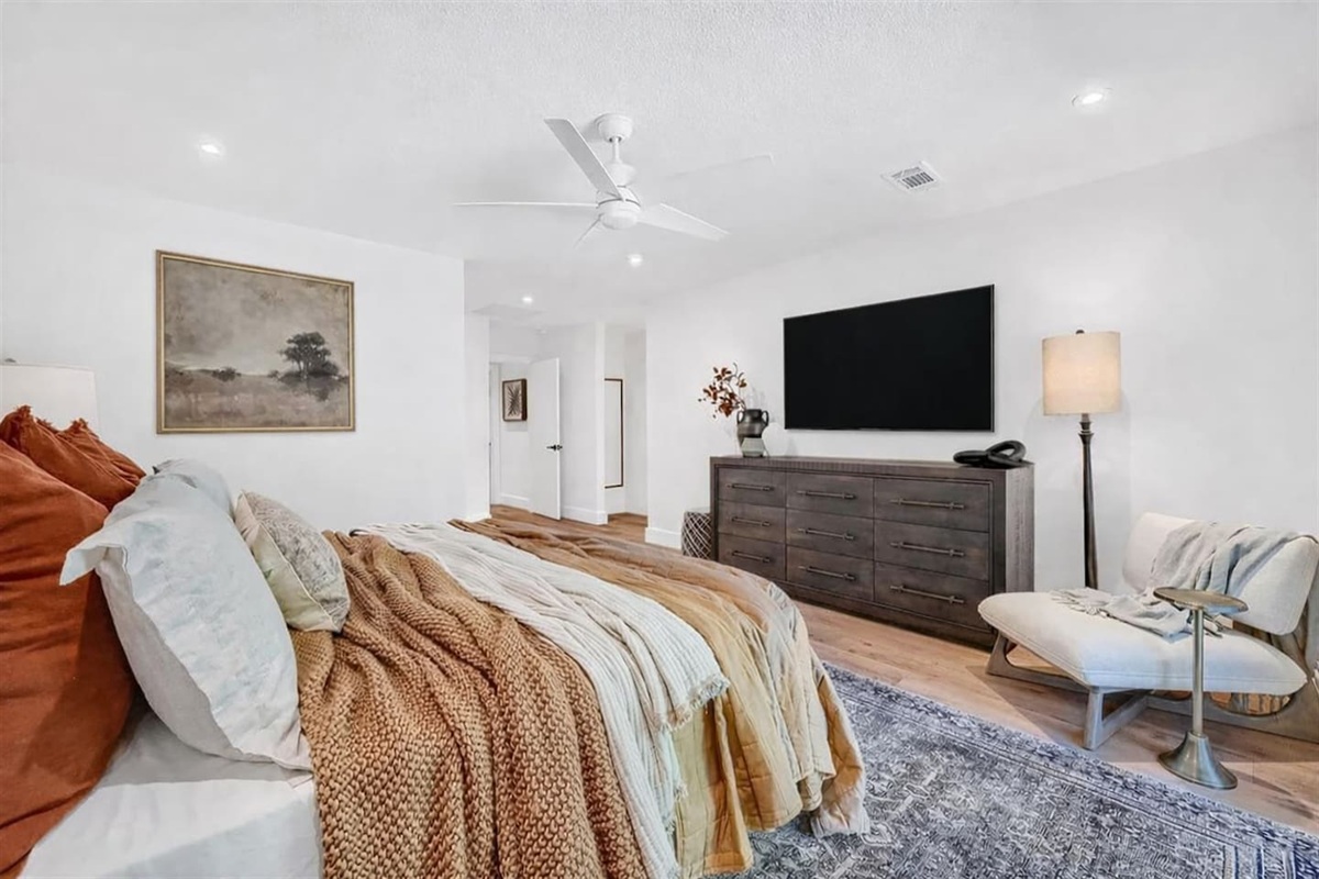 Primary bedroom with king bed, TV, large closet, well sized dresser, room darkening curtains, fan, and attached bathroom with heated floors and huge shower. 