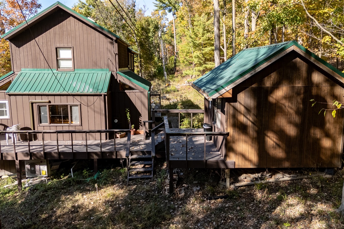 Elevation view of cabin’s deck & steps leading toward forest and lake path.