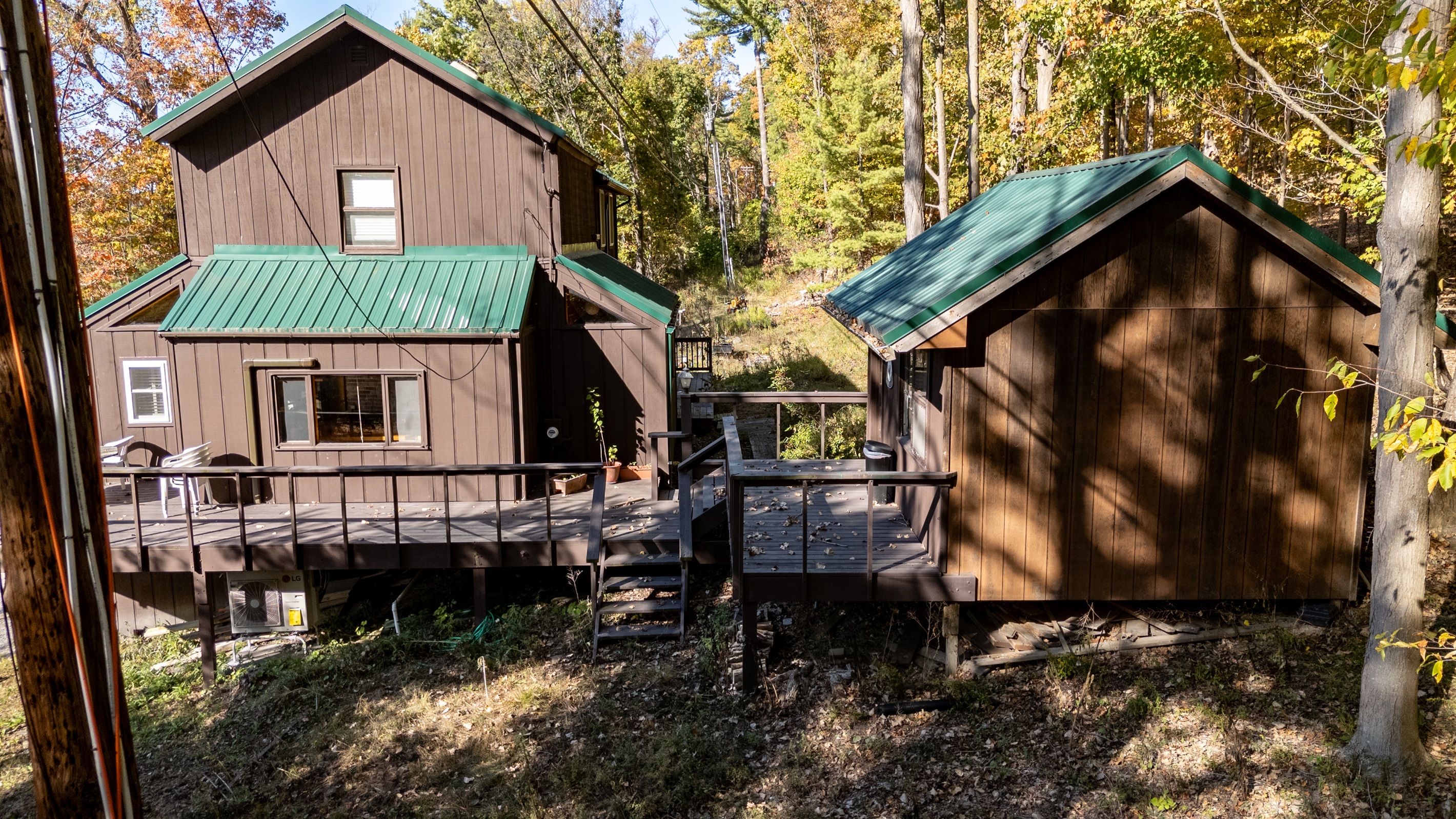 Elevation view of cabin’s deck & steps leading toward forest and lake path.