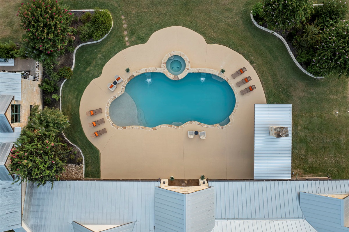 Bird's-eye perspective of a beautiful home and its expansive grounds, featuring a sparkling swimming pool and hot tub.