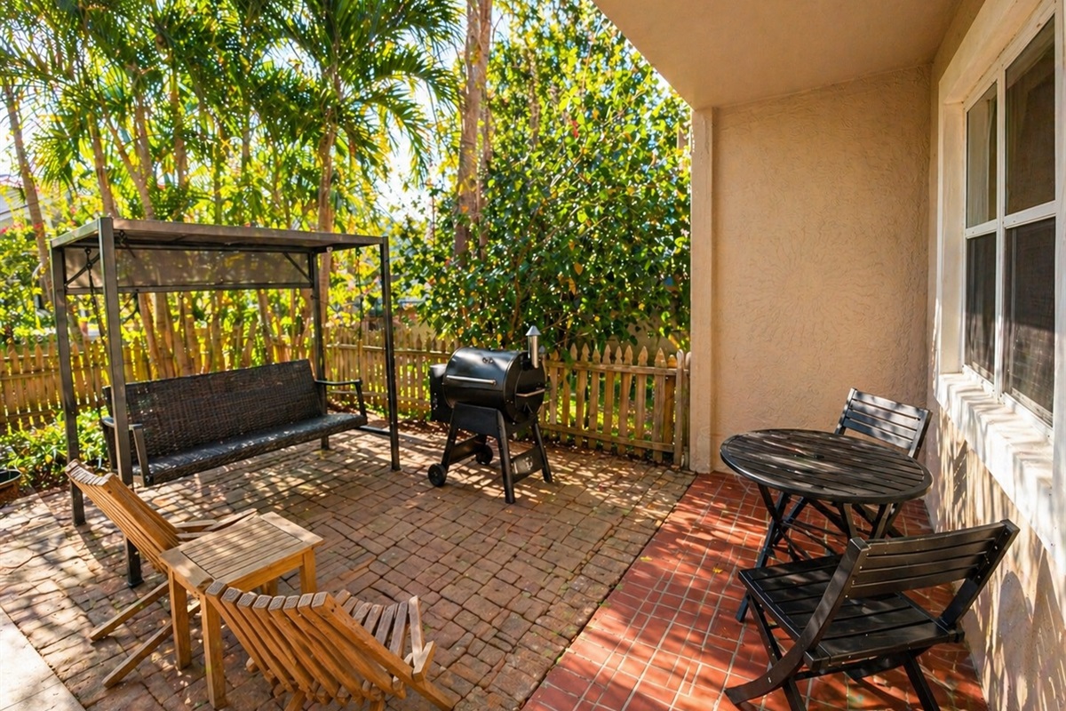 backyard with smoker, grill, swinging chair and fenced yard with Christmas lights at night 
