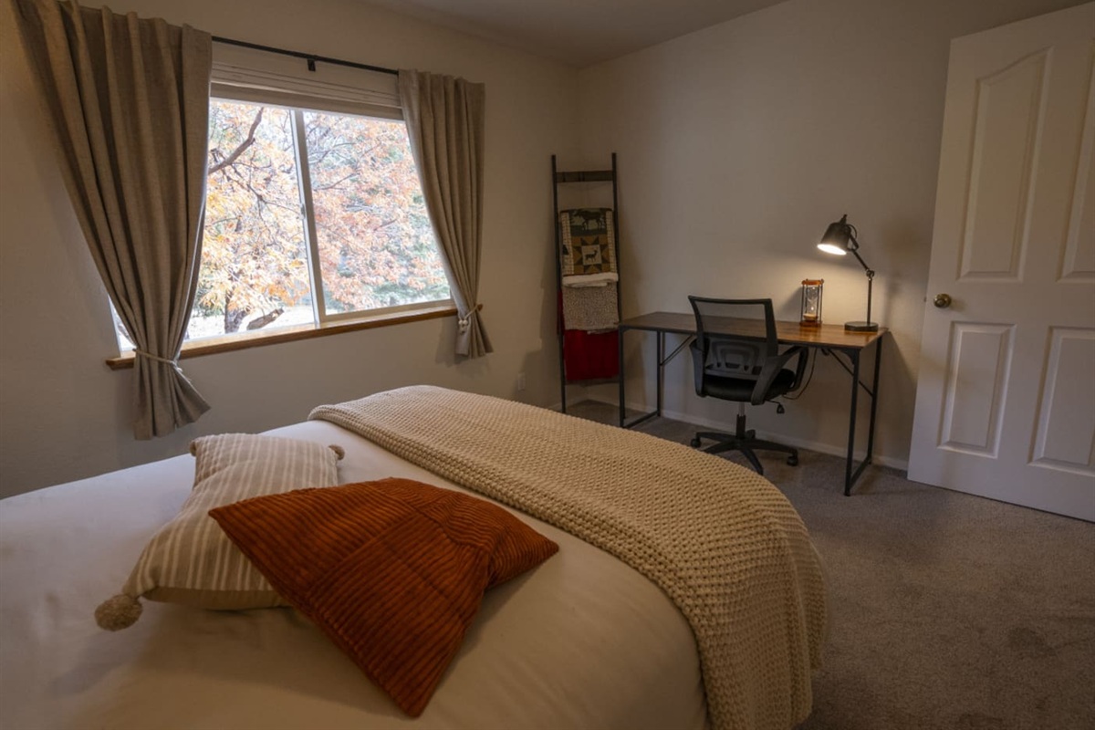 Queen bedroom with soft bedding, and a small desk perfect for working.