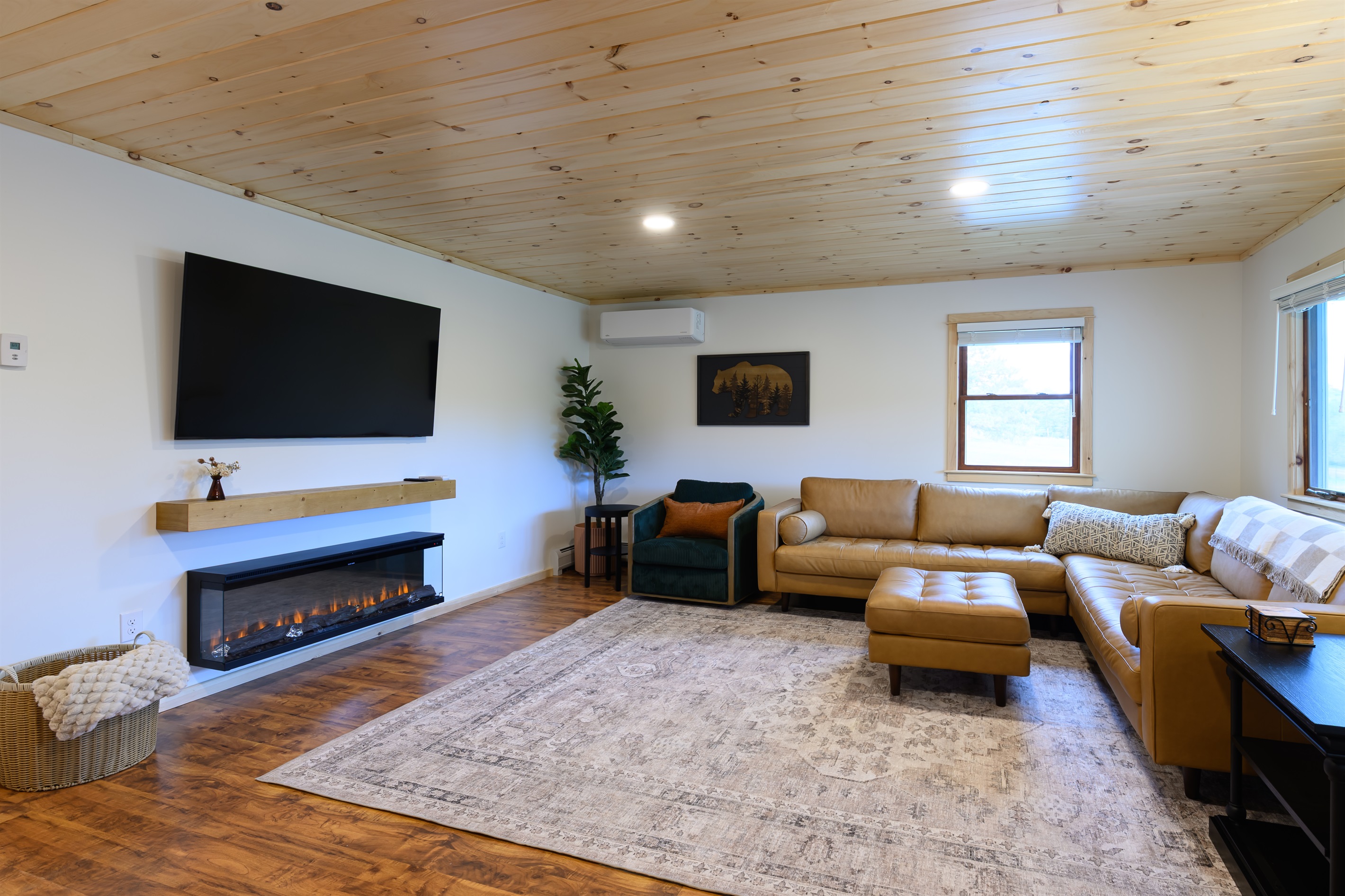 The living room features a 65 inch smart tv and an oversized Article leather couch