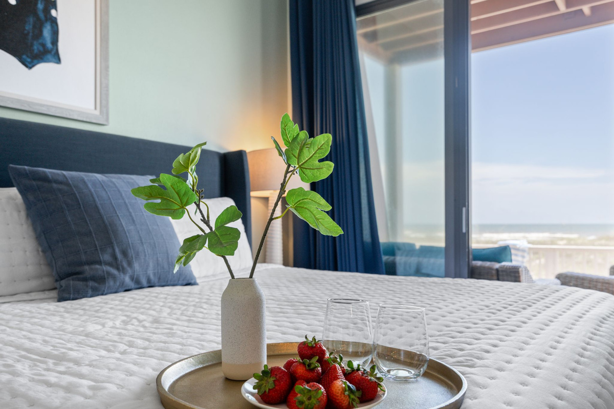 Cozy bedroom with a private ensuite and sliding glass doors opening to a spacious deck with breathtaking gulf views.
