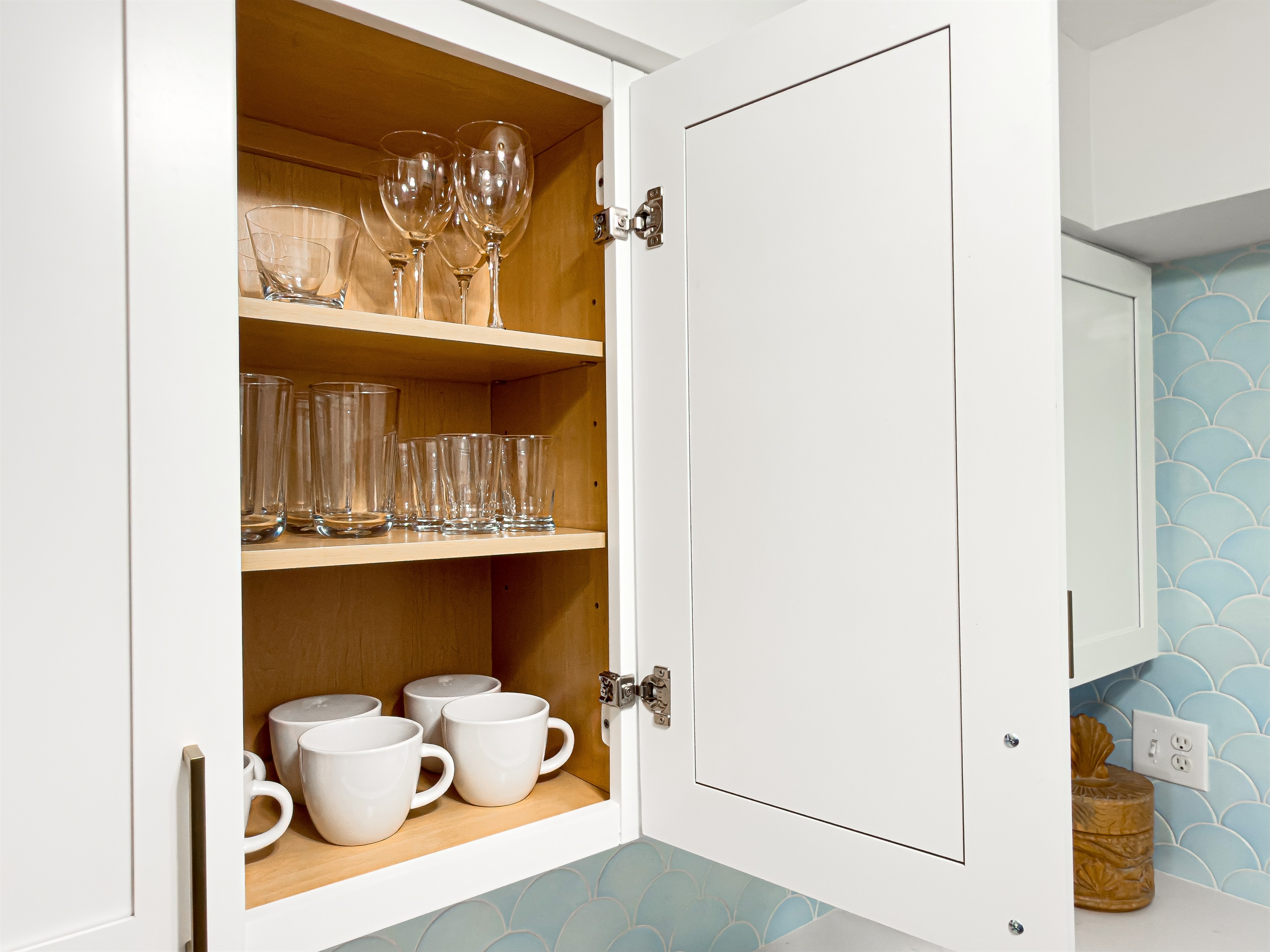 Wine glasses are clean and ready in the upper cabinet for a quiet drink at the island after the sun goes down.