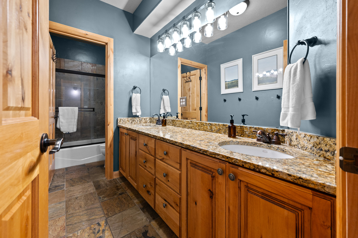 Spacious bathroom with granite counters and a tub/shower combo.