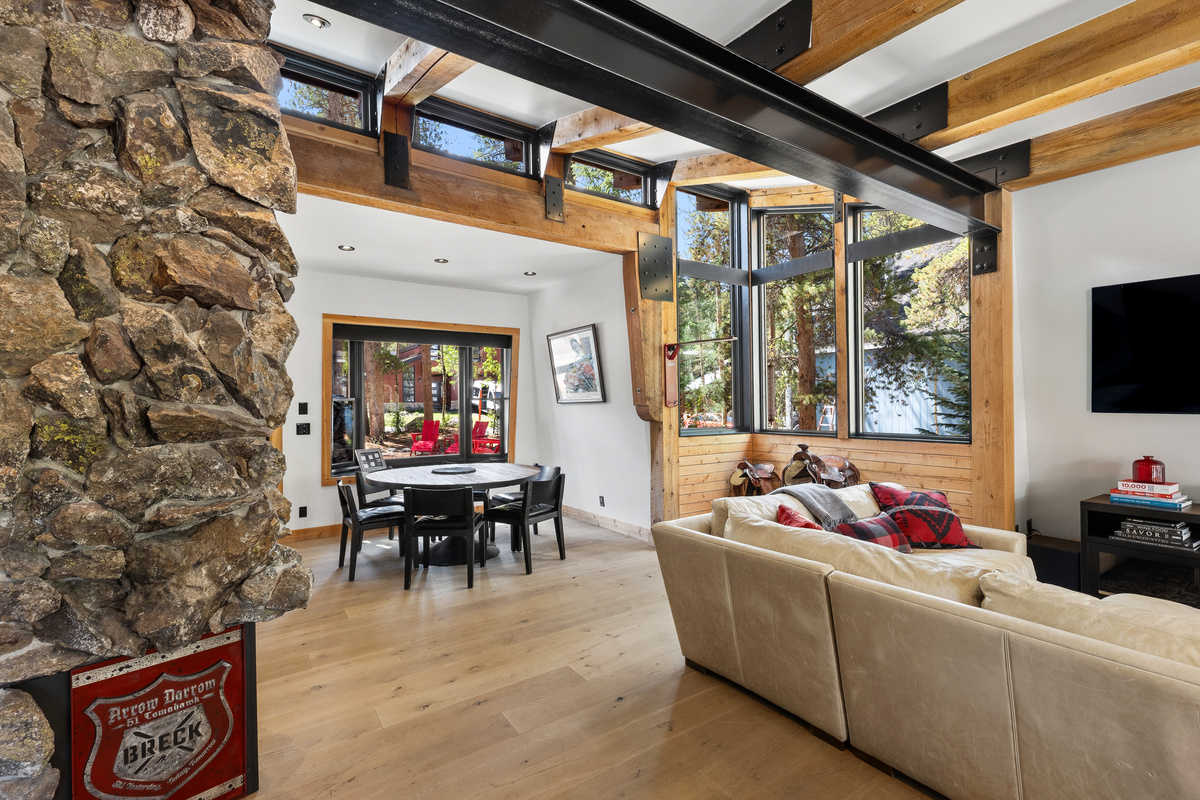 Vaulted ceilings with intricate beam work and a rock fireplace are in the center of the main living area. 