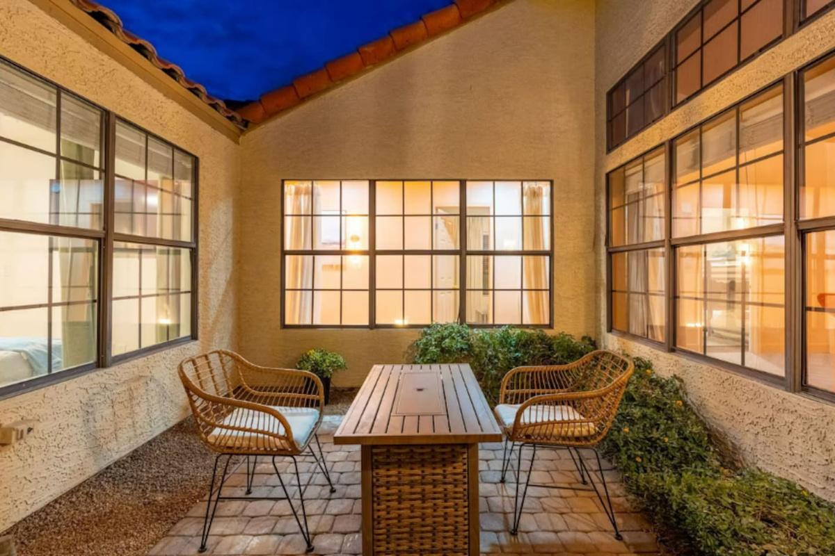 Intimate courtyard with rattan seating, wooden table, and floor-to-ceiling windows—a peaceful retreat for morning coffee or evening conversation.