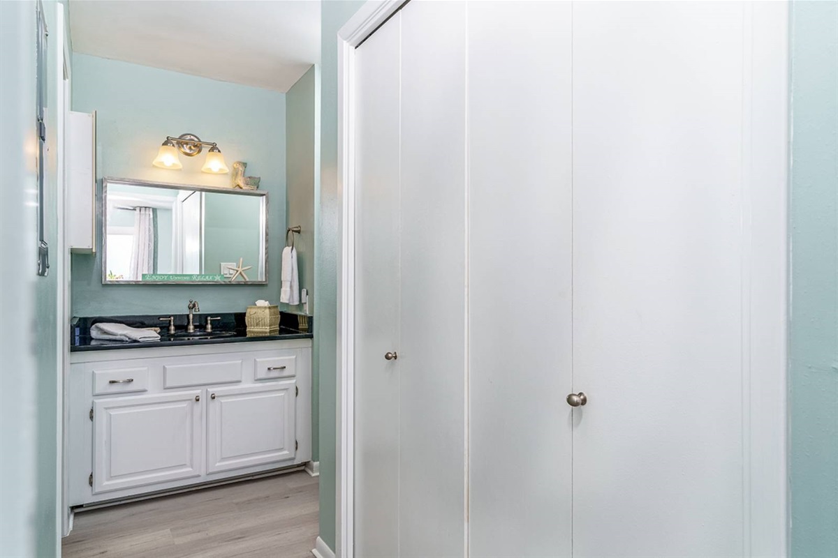 Dark granite vanity and warm coastal touches. One of two full bathrooms at this dune-front retreat for up to 6 guests.