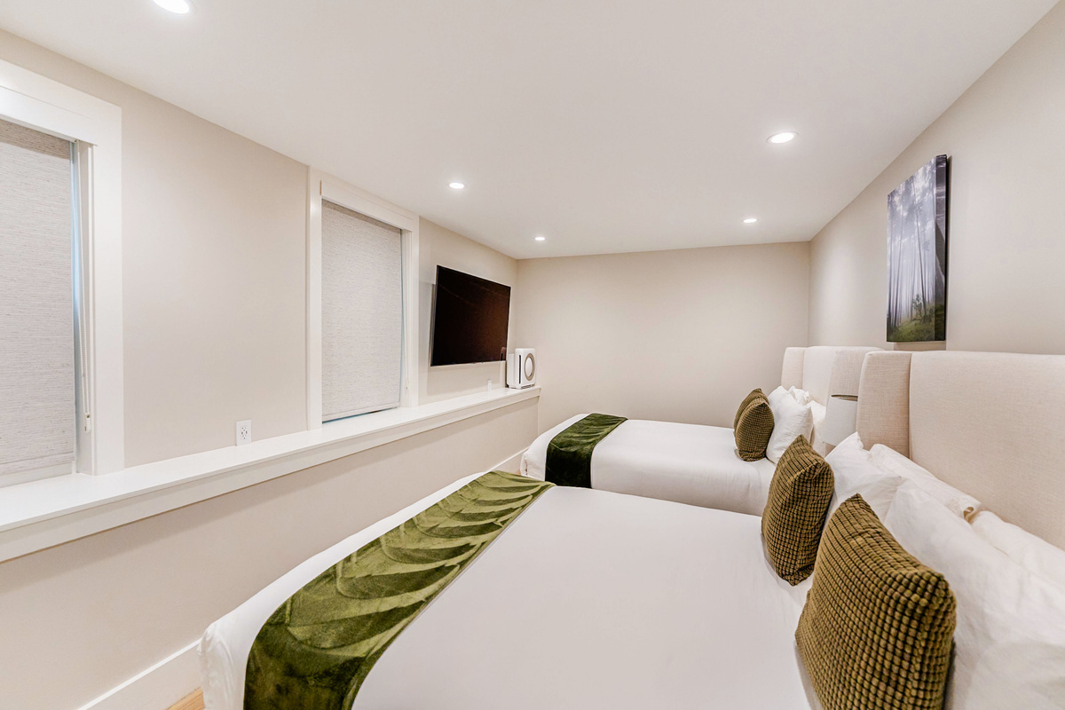 Large bedroom w/ 2 brand new Avocado Green queen beds & luxury bedding, 3 nightstands w/ built-in charging stations, built-in closet for storage & 65" NeoQLED 4k smart TV