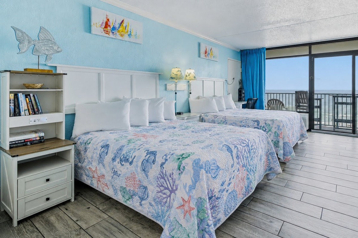 Two beds, a shelf of good reads, and the ocean waiting at the end of the room. ⭐
