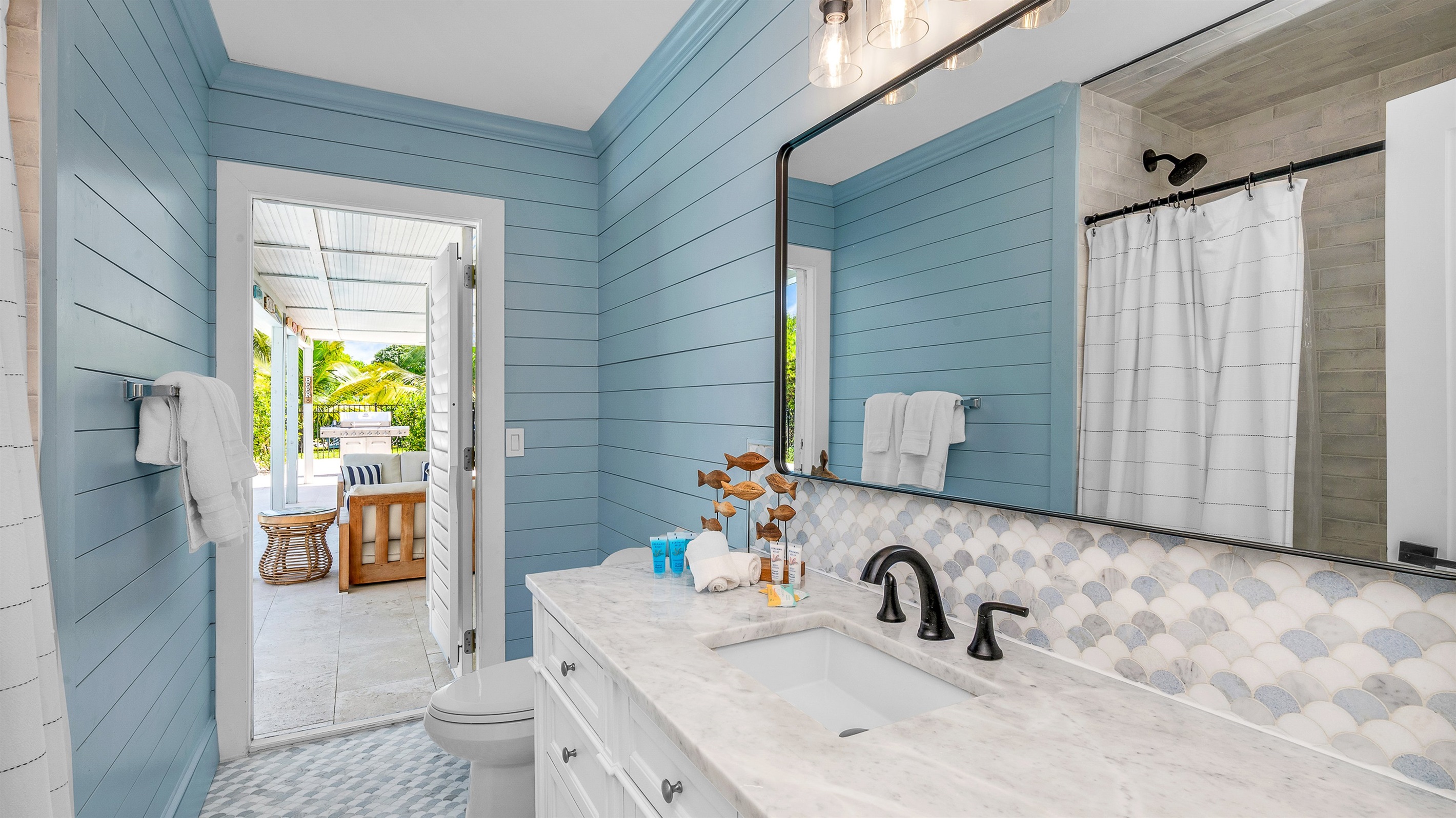 The second bathroom combines coastal charm with modern style, featuring blue shiplap walls, matt black fixtures, and a bright, airy design that brings a refreshing spa-like feel to the space