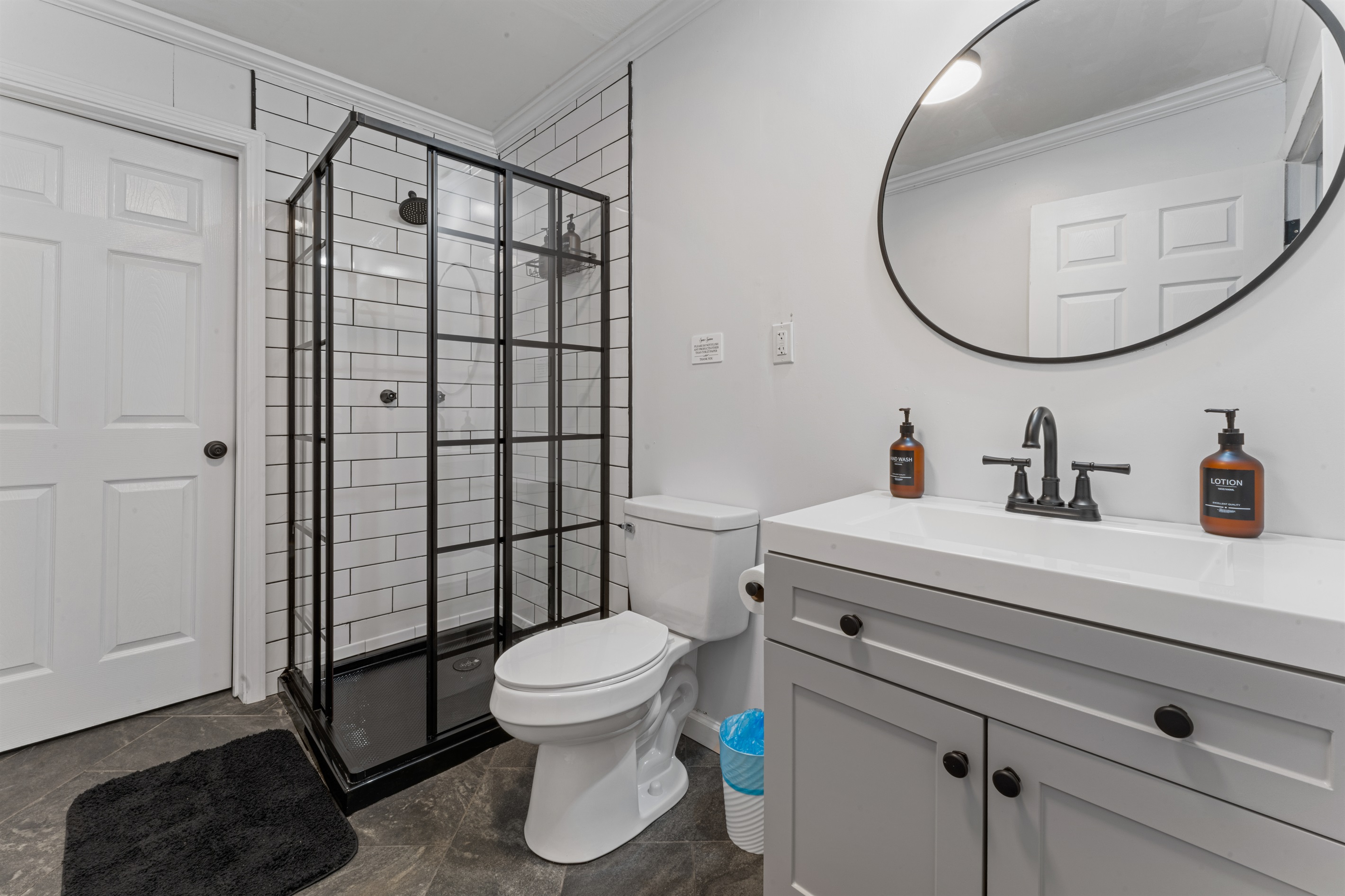 Modern, spotless bathroom featuring a stylish black-framed walk-in shower, spacious vanity, and all essentials provided for a comfortable stay.