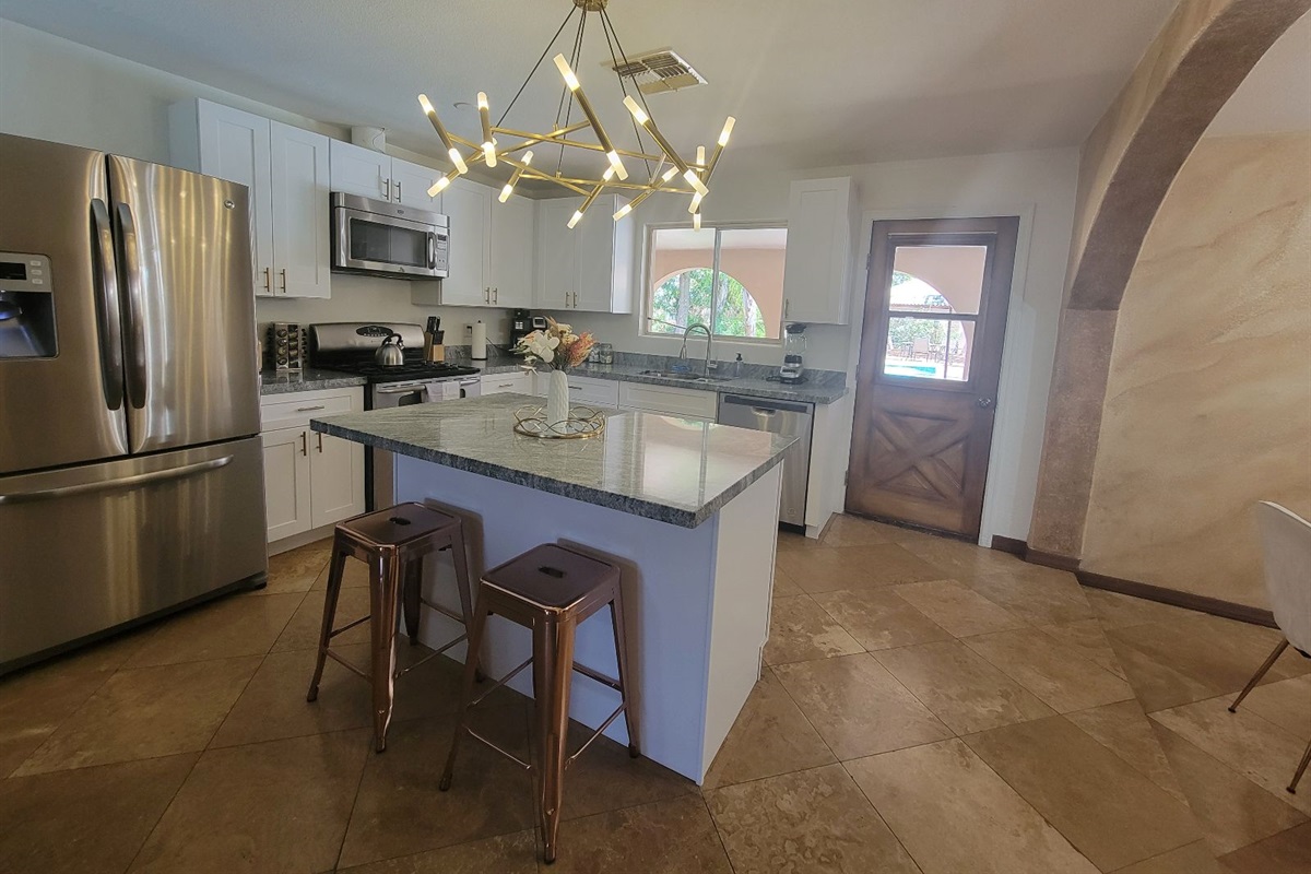This modern kitchen features stainless steel appliances, sleek granite countertops, and a central island perfect for morning coffee or evening cocktails.