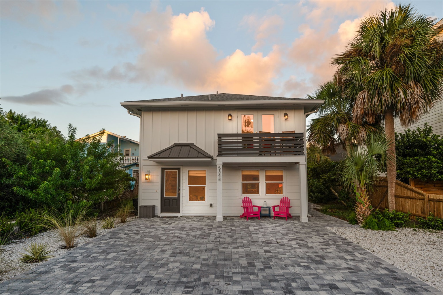 Here’s a beautiful sunset shot, with golden hues and fluffy pink clouds. Below, you can spot two pink chairs nestled under the outdoor balcony, which also features a cozy seating area. This serene space is just off the master bedroom suite 