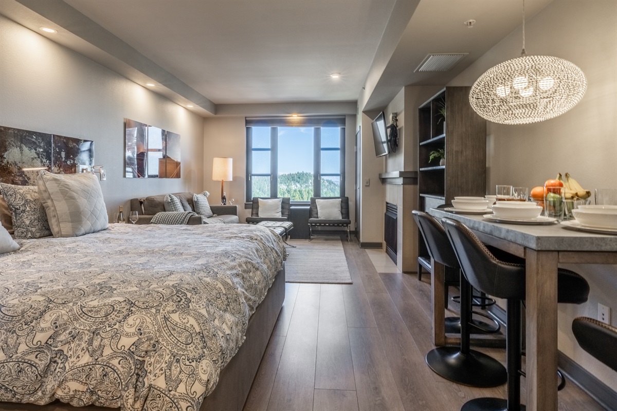 The open studio layout blends sleeping, dining, and living spaces seamlessly, with a king bed, bar-height table, and comfortable lounge area all thoughtfully connected.