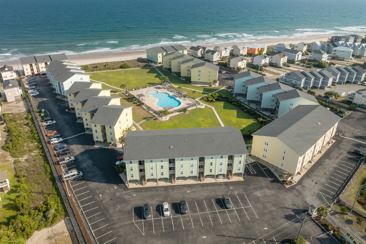 A full aerial of Surf Condos showing the pool, green space, and beachfront setting