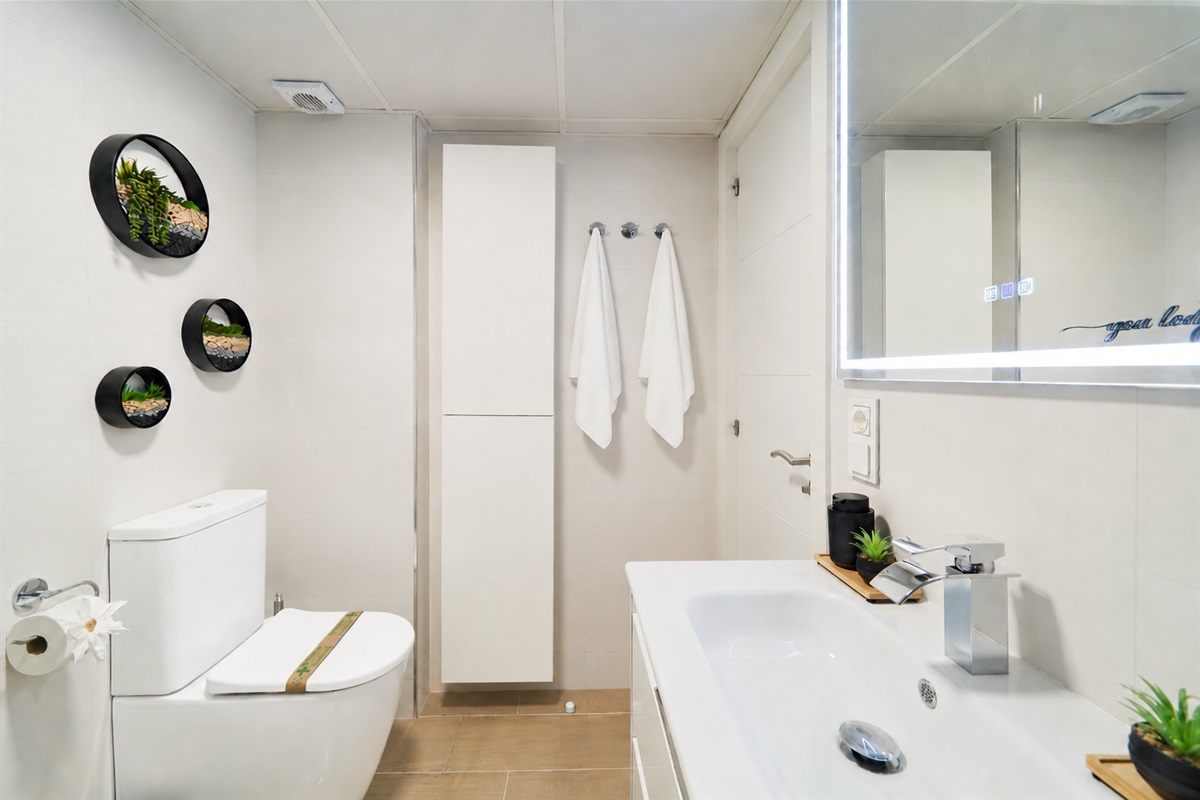 Modern bathroom with walk-in rain shower, stone accent wall, LED mirror, and fresh spa-like touches for your comfort.
