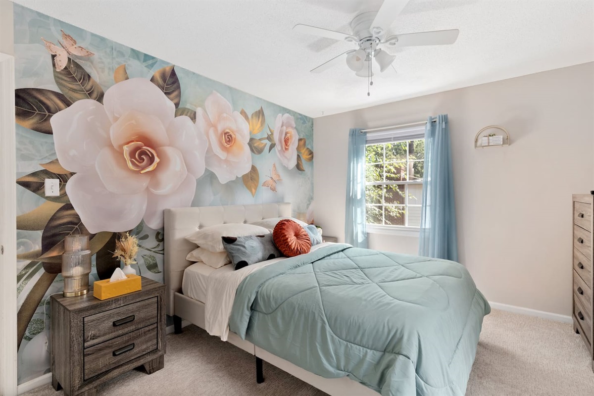 Whimsical and spacious bedroom featuring custom floral mural, queen bed, and plenty of natural light.