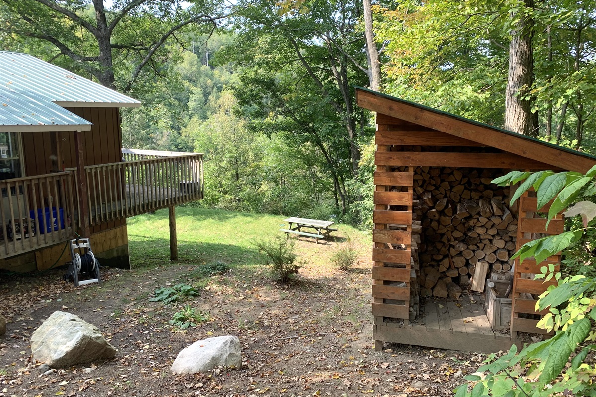 Approach area to cottage from driveway and woodshed showing lawn and fire pit area below