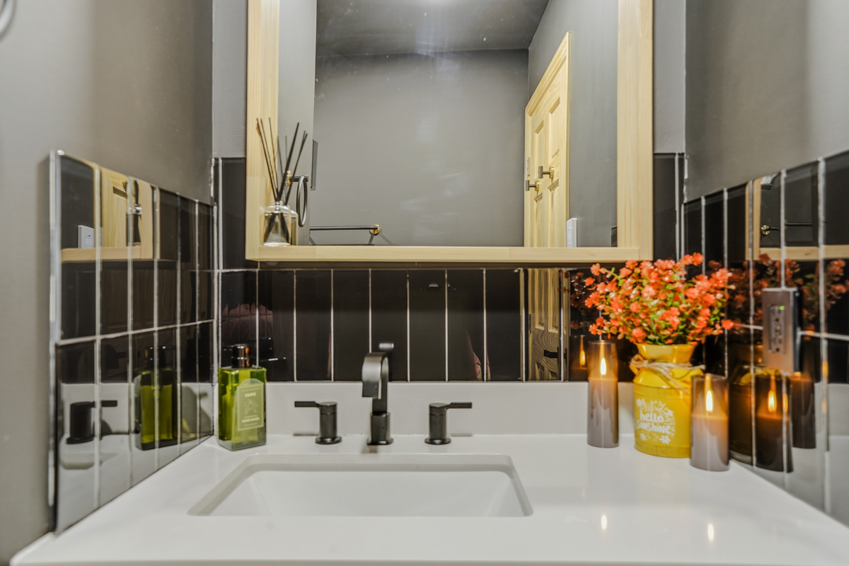 Primary bathroom vanity — double sinks, gold fixtures, dark tile, and ambient lighting